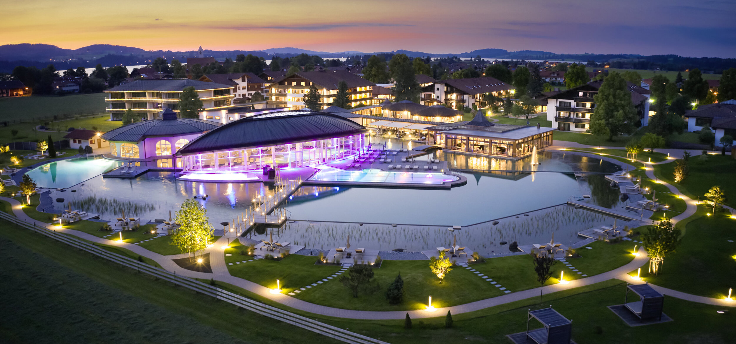 The „König Ludwig” Wellness & SPA Resort Allgäu in Schwangau in the evening hours with the lighting switched on & illuminated pool