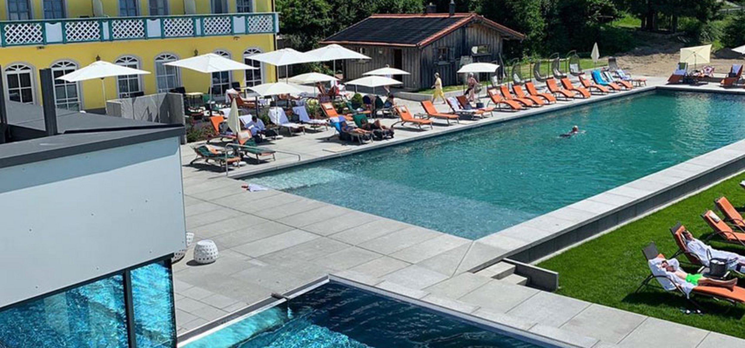 Natural pool with Balena system with loungers and guests at the “Angerhof” sports and wellness hotel in St. Englmar