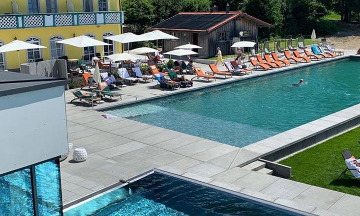 Natural pool with Balena system with loungers and guests at the “Angerhof” sports and wellness hotel in St. Englmar