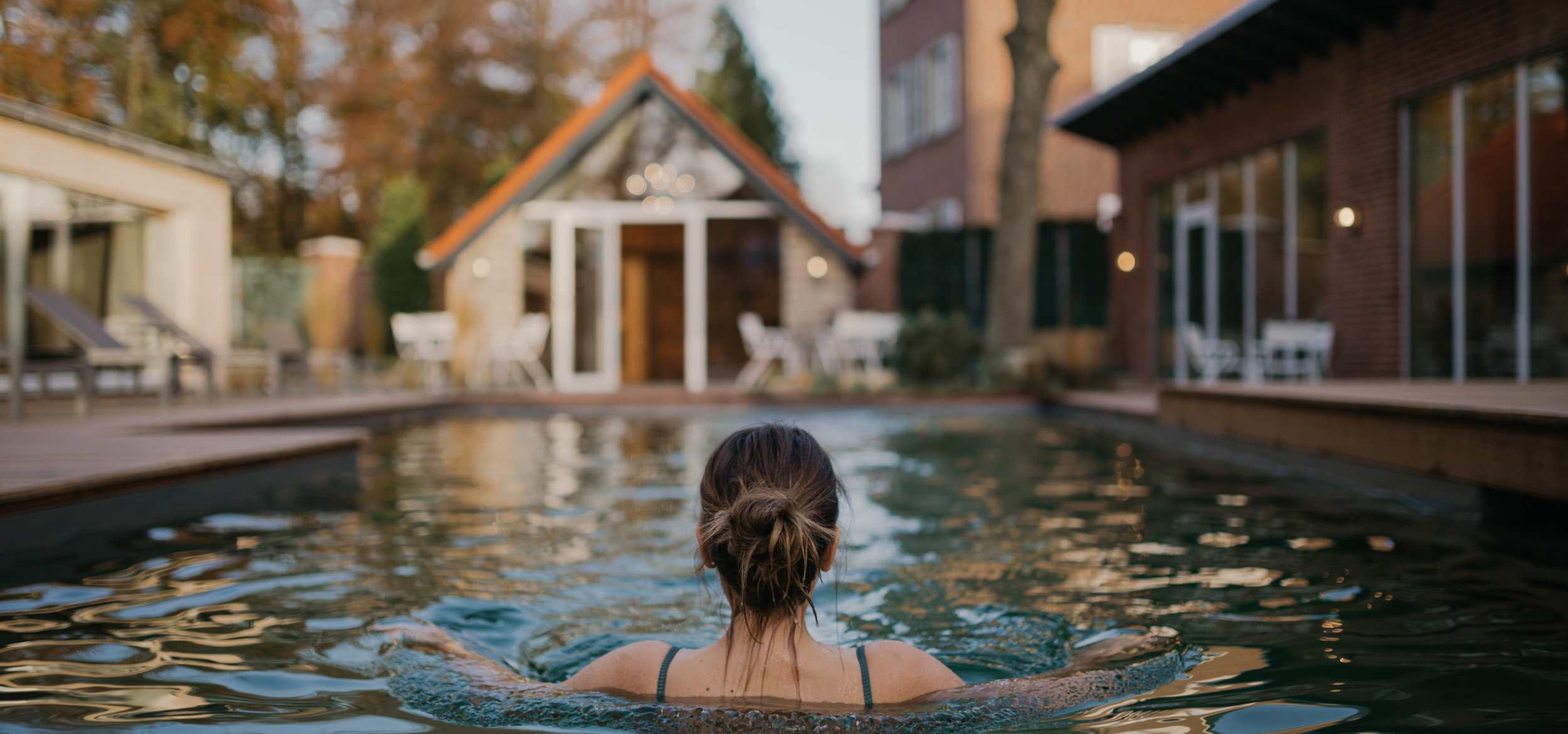 A woman bathing in the swimming pool of the Hotel-Residence “Klosterpforte” in Marienfeld, in the background adjacent buildings