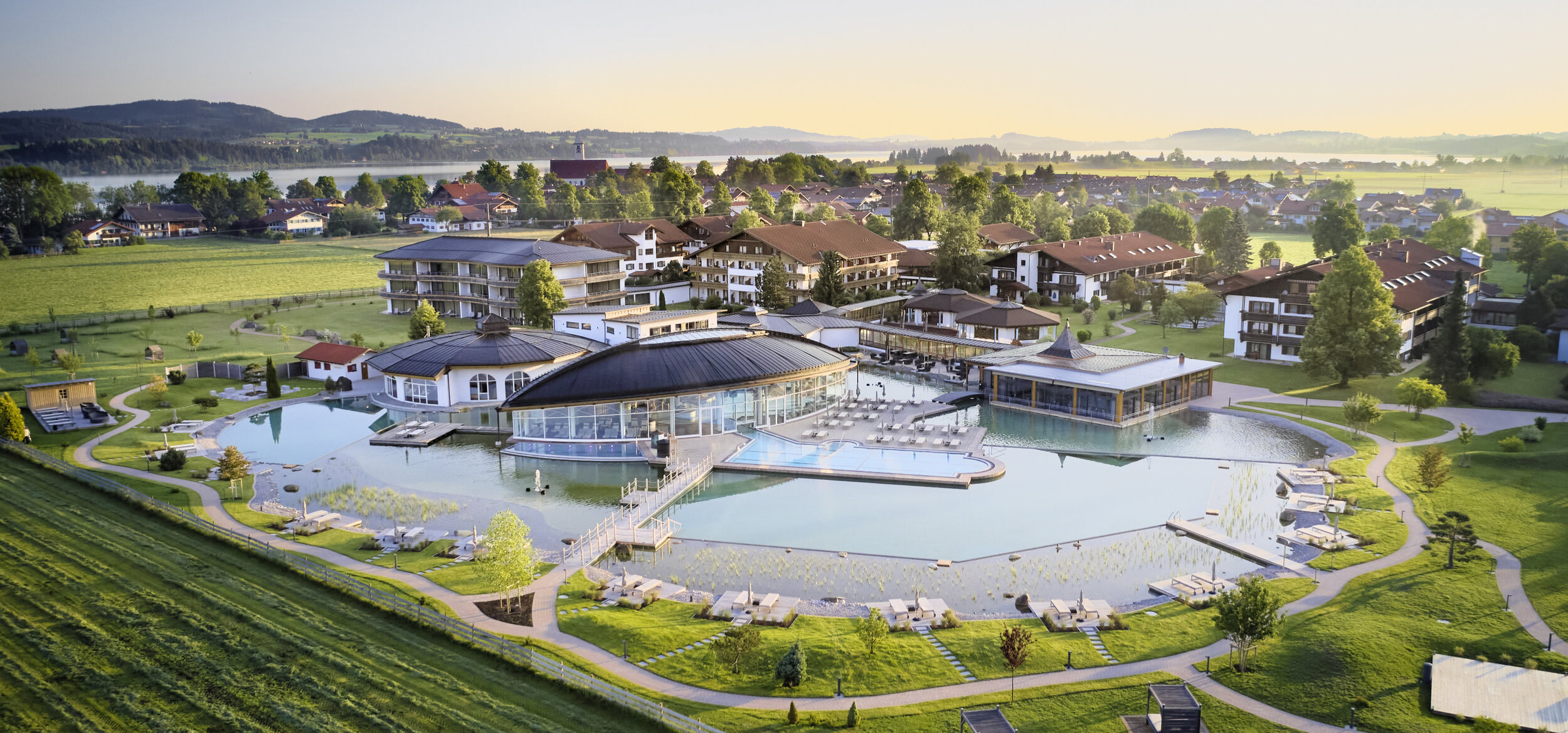 The “König Ludwig” Wellness & SPA Resort Allgäu in Schwangau photographed from the air, mountains and a lake in the background