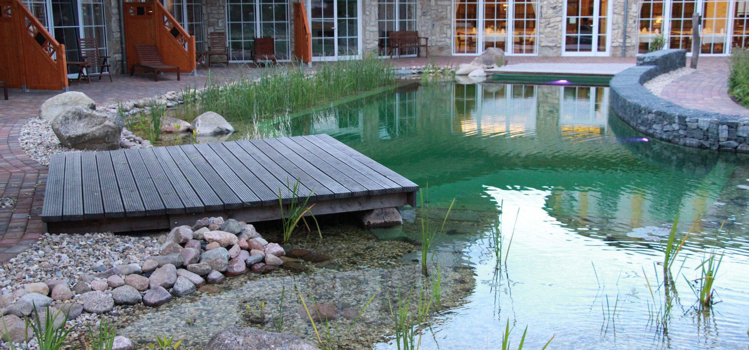 Swimming pond with Balena system with lounger and bank planting at the wellness hotel SPA & nature resort “Seeschlösschen” in Senftenberg